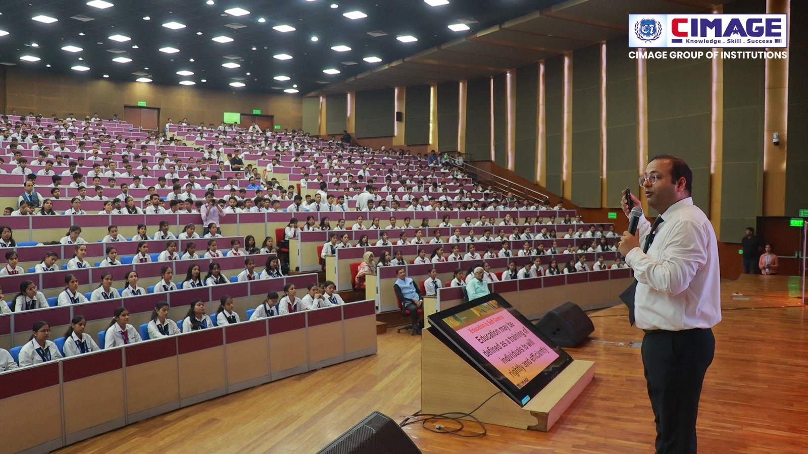 Speaker addressing a packed student auditorium during a campus event