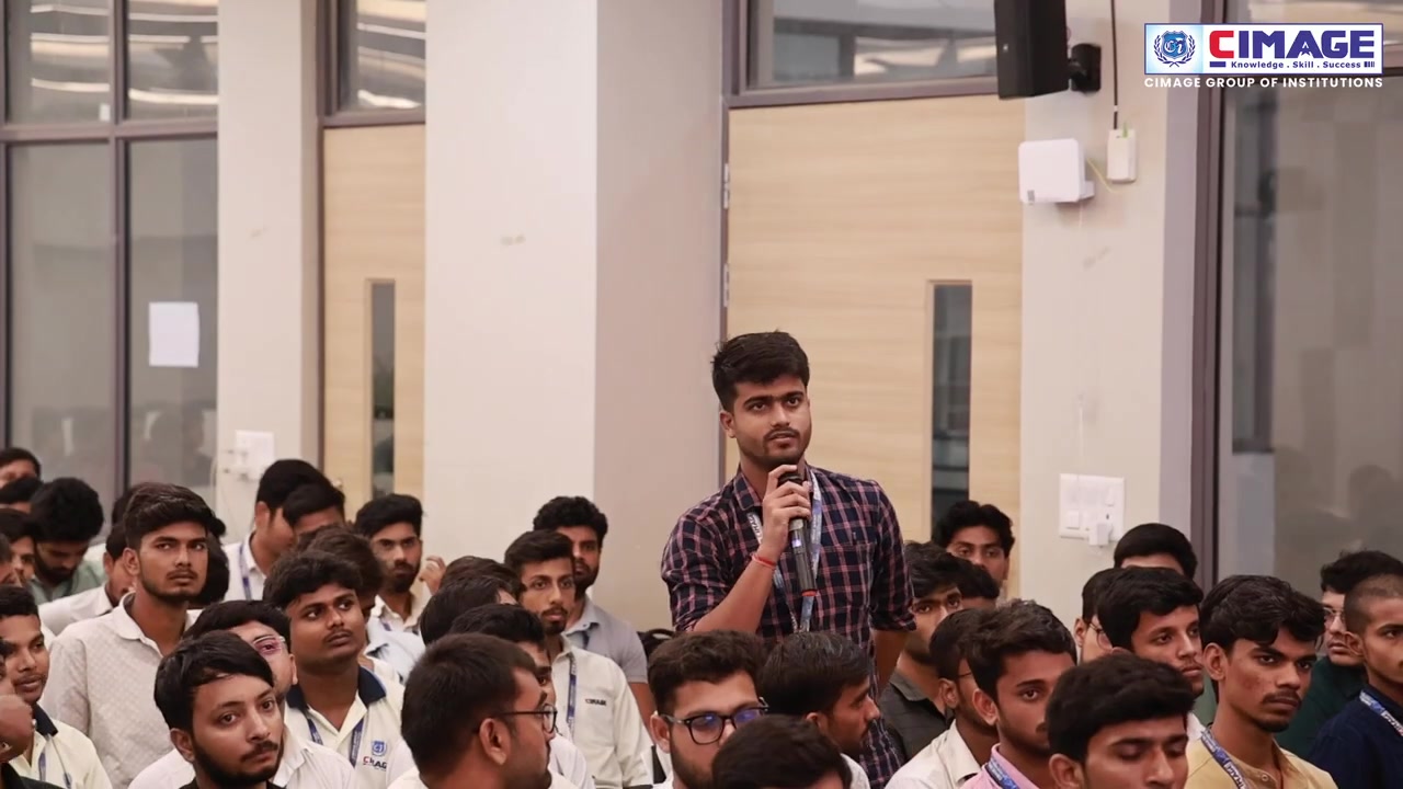 A student standing up in the audience holding a microphone.