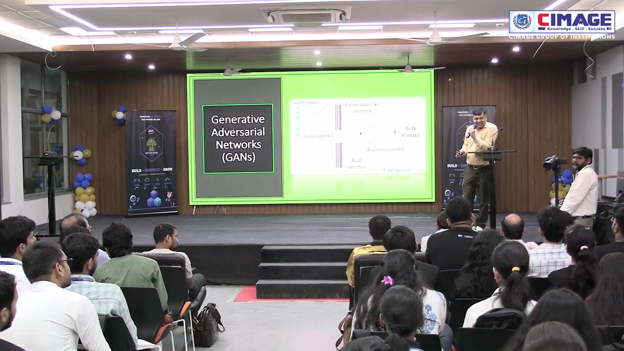 A speaker stands at the podium presenting a slide titled Generative Adversarial Networks (GANs).